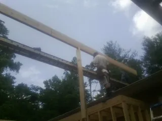 Carpenter setting a ridge beam over a new addition frame — Ice Dam Removal by Roofing Brothers in Garrett