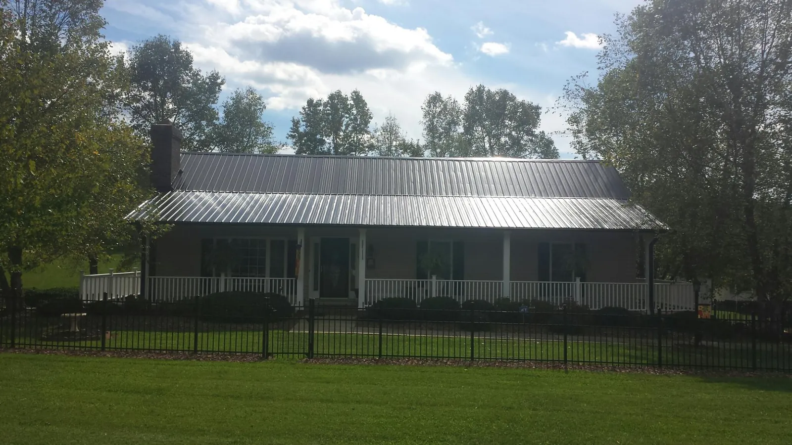 Gray metal roof on a brick ranch with a full width front porch — Gutter Guard Installation work by our crew in Garrett