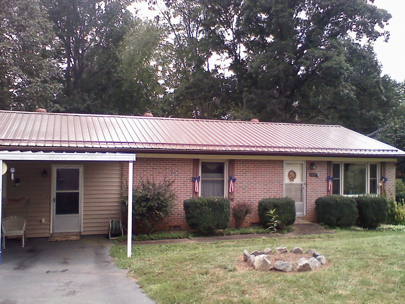 Bronze metal roof and carport on a brick ranch home — Roof Repair work by our crew in Garrett