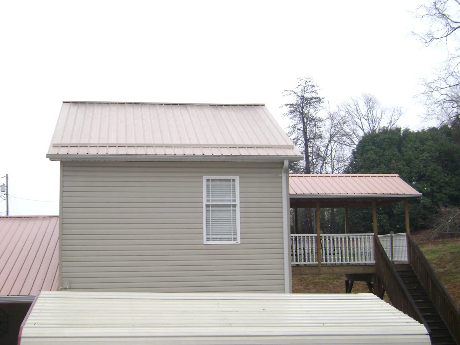 Tan metal roofs on a two story addition and attached porch, from a Roof Replacement job in Garrett
