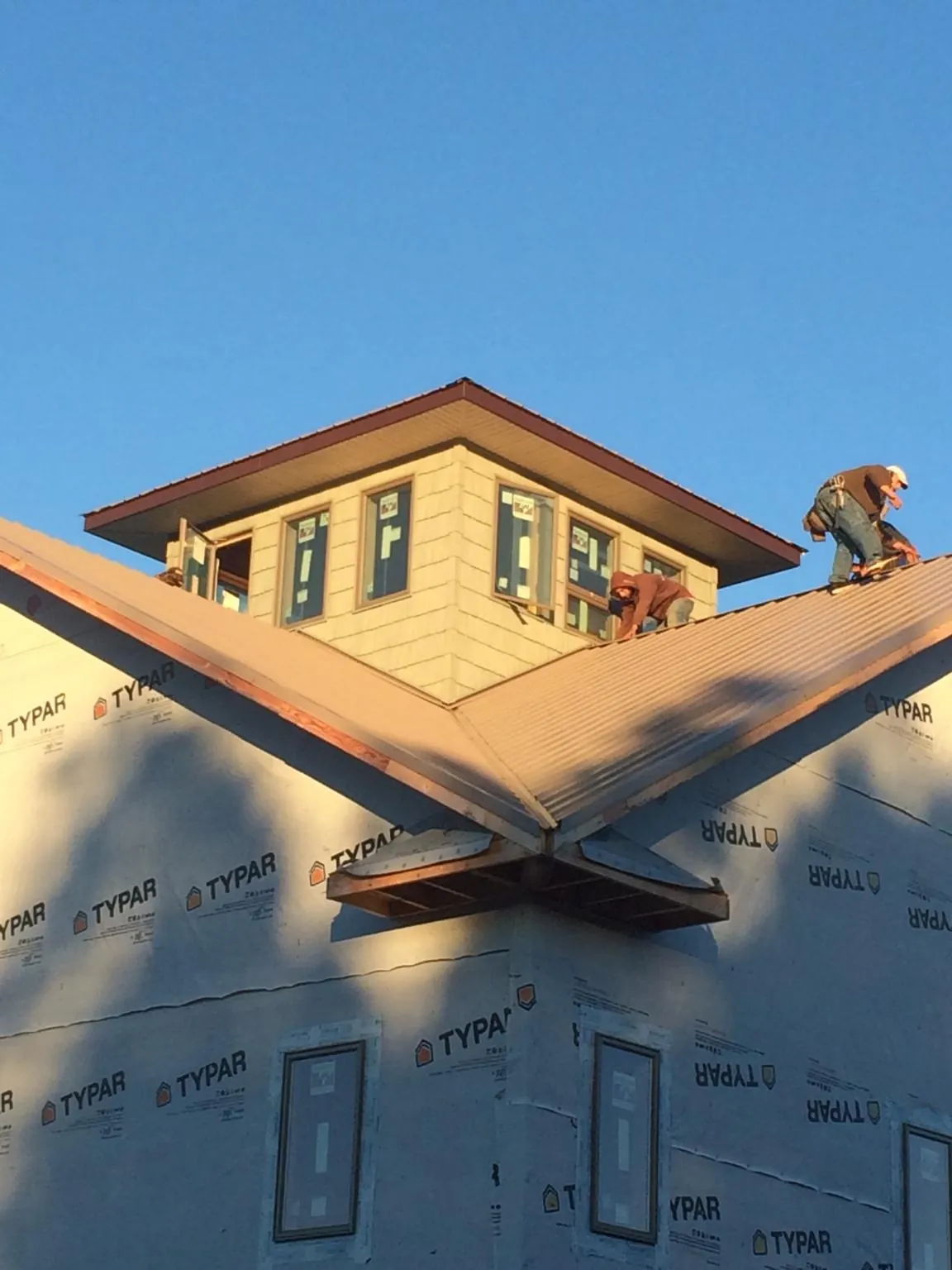 Roofers working around a rooftop cupola on a new metal roof at sunset — Roof Waterproofing in Garrett by Roofing Brothers